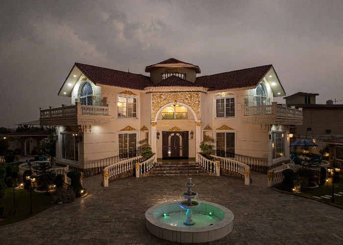 Luxury farmhouse exterior in Islamabad at dusk with fountain and lighting, ideal setting for premium brand photoshoots