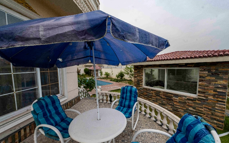 Outdoor patio seating with umbrella near farmhouse, ideal cozy location for family photoshoots with natural light and relaxed poses