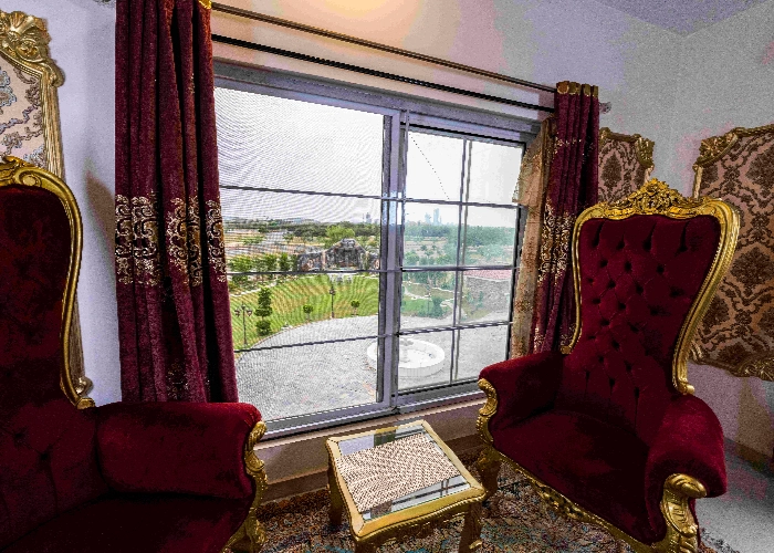 Luxury royal chairs by window with scenic farmhouse view in Islamabad, ideal indoor setting for premium brand photoshoots